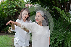 An old elderly Asian woman and exercise in the backyard with her daughter.  Concept of happy retirement With care from a caregiver
