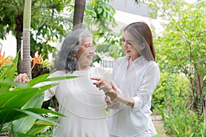 An old elderly Asian woman and walking in the backyard with her daughter.  Concept of happy retirement With care from a caregiver