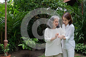 An old elderly Asian woman and walking in the backyard with her daughter.  Concept of happy retirement With care from a caregiver