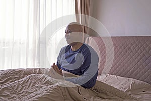 Old elderly black man. African American person waking up on bed in bedroom at home in early morning and stretching hands. People