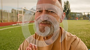 Old elderly Caucasian man stadium outside meditating on lawn sitting closed eyes smiling harmony retirement