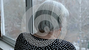 Old Elderly Caucasian Woman With Gray Hair Looks Out Of Window