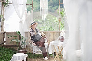 Old elderly senior woman resting relaxing sitting in wooden gazebo in garden park