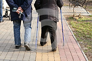 Old elderly man and woman walking with a cane
