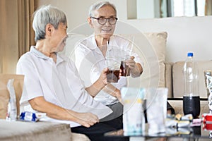 Old elderly people drinking soft drink,eat junk food,snacks on the table at home,asian senior women holding glass of beverages