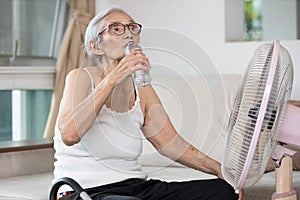 Old elderly woman drinking a bottle of water,keeping body water balance,drink a lot of water to prevent dehydration in heat hot photo