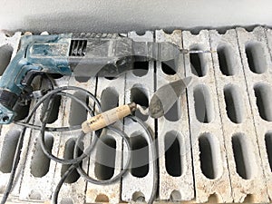 Old electric drill on gray brick wall background material of construction