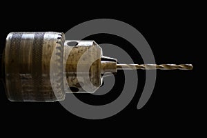 Old electric drillhead with drill isolated on black background.