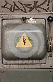 Old electric high-voltage switch with a painted danger sign. Abstract danger background.