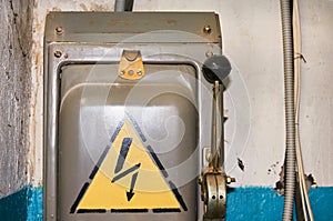 An old electric high-voltage switch with a painted danger sign.