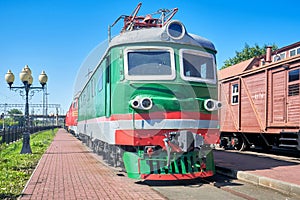 Old electric locomotive stands at the station on rails