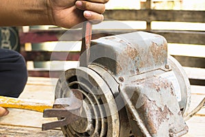 Old electric motor and man working equipment repair on wooden floor background.Background mechanic or equipment