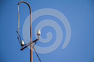 Old electric pole with ceramic insulators and wires over a blue sky, selective focus