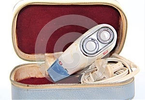 Old electric shaver in a case on the white background