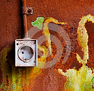 Old electrical outlet on rusty iron wall