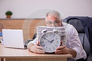 Old male employee in time manegement concept photo