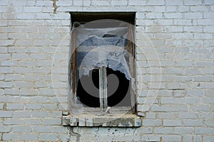 Old empty window with wooden frame on a gray brick wall of an abandoned house