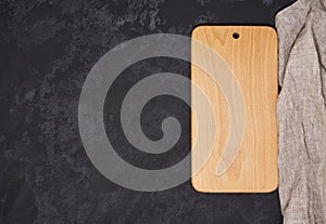 Old empty wooden cutting board on black background, top view