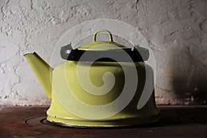 Old enameled kettle on the stove on a white background in dark colors.
