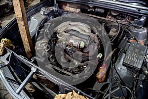An old engine under repair  in an old gray car