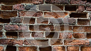 Old eroded brickwork with knocked out bricks. Erosion of an old faded red brick wall