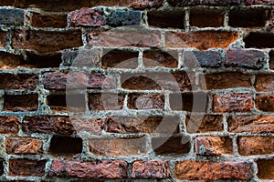 Old eroded brickwork with knocked out bricks. Erosion of an old faded red brick wall
