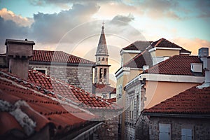 Old European city skyline with orange tile roofs and tower in front of dramatic sunset sky with antique architecture in old Europe