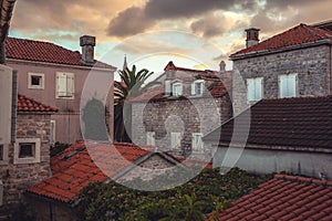 Old European city street view with orange tile roofs in antique architecture during beautiful sunset in retro vintage style