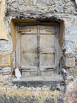 Old European Home with Wooden Window Among a Crumbling Stone Wall