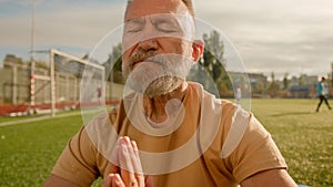 Old European man pensioner meditating stadium city outdoors clarity of mind looking at camera smiling recreation balance