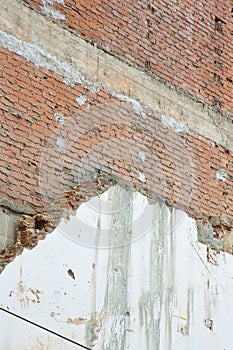 Old exposed brick wall without protective plaster with damaged reinforced concrete beam