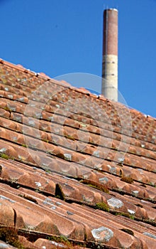 Old factory roof with roof tiles and brick chimney