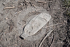 Old faded and dingy plastic bottle as litter in the nature