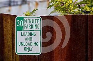 Old faded worn metal 30 minute parking sign with green text