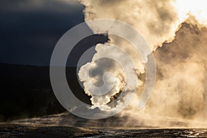 Old Faithful geyser exploded smoke with warm sunlight in early morning