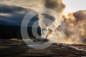 Old Faithful geyser exploded smoke with warm sunlight in early morning