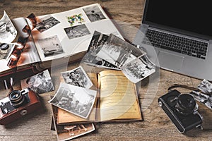Old family photos and album on wooden background. Vintage pictures, camera, notepad and modern notebook photo