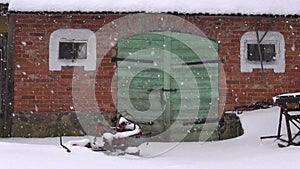 Old farm green door on red wall and winter snowfall