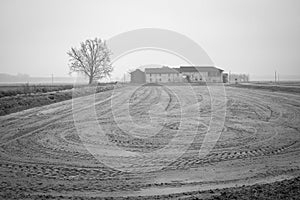 Old farm with its uncultivated field. Black and white photo