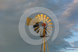 Old farm windmill shining in the golden sunlight at dusk