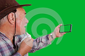 An old farmer emotionally argues looking at the chroma key screen of a mobile phone.