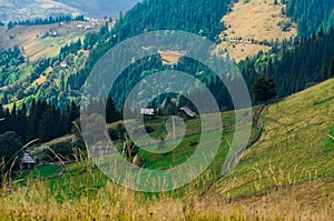 An old farmer's wooden house stands on an elephant mountain near a haystack against the backdrop of mountain peaks