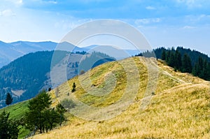 An old farmer's wooden house stands on an elephant mountain near a haystack against the backdrop of mountain peaks