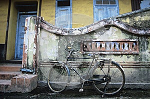 Old fashioned bicycle left by crumbling wall photo