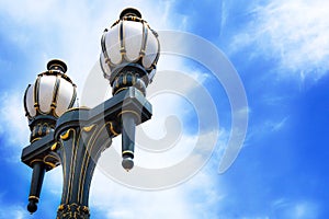 Old-fashioned black and gold streetlamps against blue sky