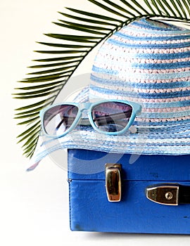 Old fashioned blue suitcase for travel and beach hat