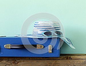 Old fashioned blue suitcase for travel and beach hat