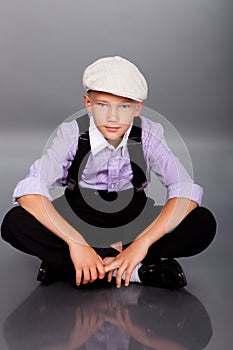 Old fashioned boy sitting on gray background