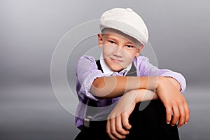 Old fashioned boy sitting on gray background