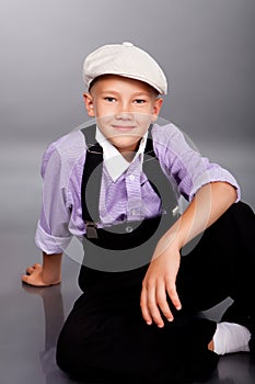Old fashioned boy sitting on gray background